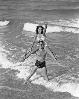 Smiling Couple Wearing Bathing Suits Playing in Surf