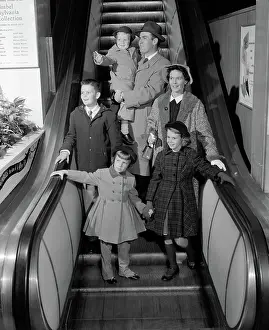 Escalators: Smiling family of 6 in winter coats going down