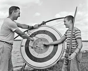 Bullseye: Smiling Father and Son by Lake Pulling Arrows out of Ar