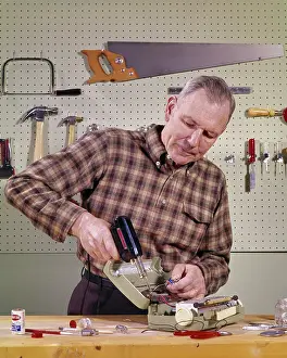 Soldering: Smiling Handyman Senior Man Holding Using a Soldering