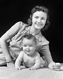 Elbows: Smiling Mother and Baby Lying on Elbows looking at Camera