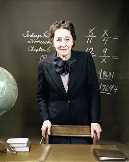 Fractions: Smiling School Teacher Standing Behind Her Desk