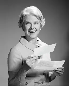 Retiree: Smiling Senior Woman looking at Camera Holding