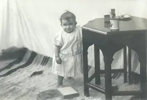 Sepia Images: Smiling toddler leaning against a table