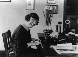 Skilled Labor: Smiling woman office worker seated at typewriter