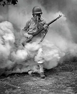 Emerging: Soldier with rifle during gas mask training at