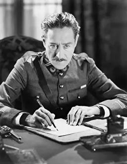 Mustaches: A soldier writing a letter with a gun next to him