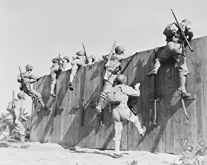 Barrier: Soldiers climb up and over a wall at Camp