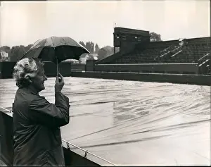Spectator in rain at Wimbledon with small umbrella