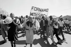 Albertina: Students marching to cemetery with grave flowers, for