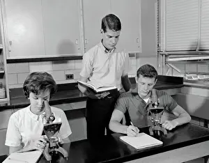Schoolrooms: Three students using microscopes two boys one