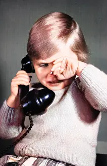 Unhappy: Studio portrait, little boy on the phone