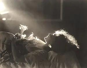 1910s 1940s: Sunlight falling on woman with flowers sleeping in bed
