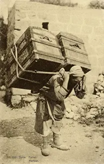 Strapping: Syrian Porter carries two enormous trunks on his back