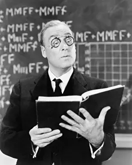 Blackboards: Teacher holding a book in front of a black board