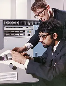 Bespectacled: Two technicians check a computer printout