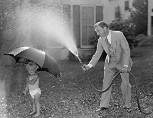 Paternal: Toddler and dad playing with hose in yard