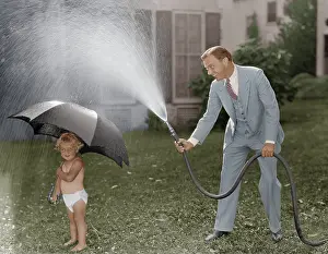 Paternal: Toddler and dad playing with hose in yard