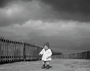 Fenced: Toddler under a stormy sky