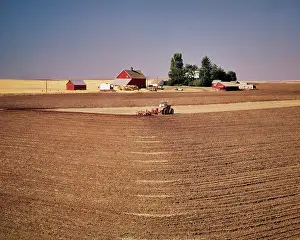 Outbuildings: Tractor Plowing Field with Farm Buildings in Background