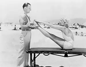 Affections: Trainer and young woman doing exercises at the beach