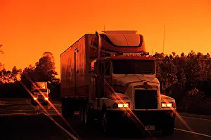 Haulage: Trucks on Highway Orange Sunset with Headlights on