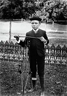 Pedaling: Turn of the century boy standing in yard next