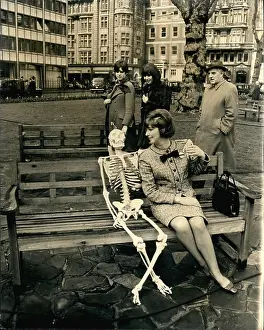 Concentrate: TV presenter with skeleton on bench, Hanover Square, London