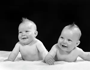 Stomachs: Two Twin Babies Smiling Lying on their Stomachs looking up