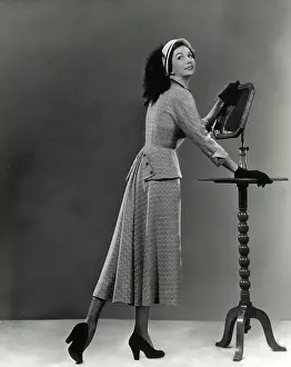 Neat: Two-piece suit - feather hat - leaning on table with mirror