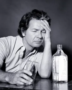 Intoxicated: Unfortunate Middle Age Man Sitting at Table Holding