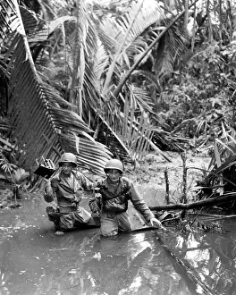 U.S. Army photographer, wading through a stream