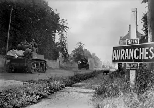 Avranches: U.S. light tanks passing a road sign for the town