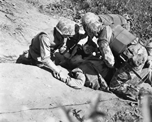 Corpsmen: U.S. Marine is given a drink of water as he waits