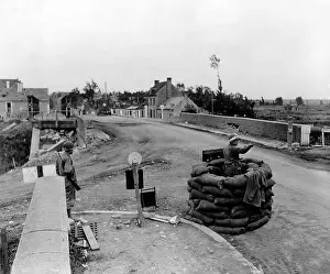 Sheltered: U.S. MP controls traffic on a bridge at Carentan