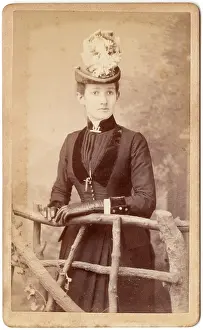 Pleating: Victorian woman standing behind a rustic fence