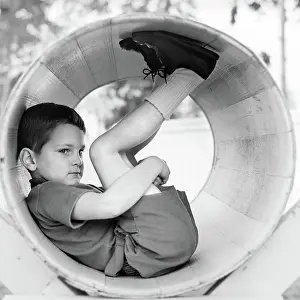 Hideaway: Side view of boy scrunched up inside tube holding
