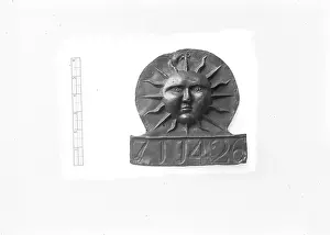 Plaque: A view of a sun face plaque on a white background