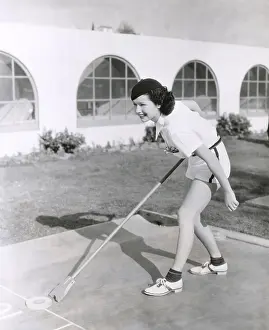 Shuffleboard: Side view of woman playing shuffleboard