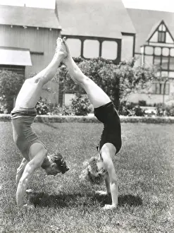 Handstand: Side view of young couple doing handstands in yard