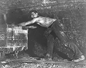 Stripped: Welsh miner in coal mine pushing truck