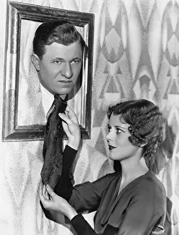 Irritated: Woman adjusting tie of man in picture frame