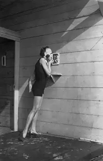 Applying: A woman applying make-up at the beach, 1926