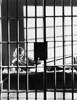 Cots: Woman through bars of jail cell