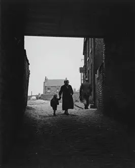Silhouetted: Woman and child walking under a bridge