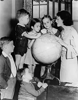 Classmates: Woman and children looking at globe