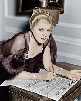 Focused: Woman doing puzzle in newspaper