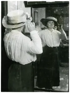 Economise: Woman examining her hat in a mirror