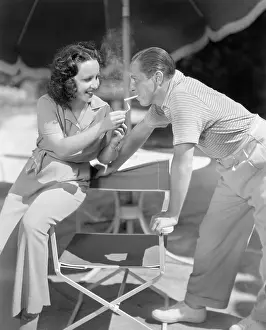 Pantsuit: Woman giving a man a light for his cigarette