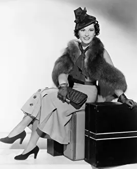 Getaways: Woman with a hat sitting on suitcases and smiling